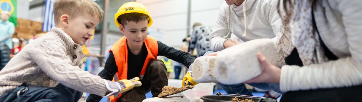 Mit viel Freude baut eine Familie auf der Kinderbaustelle der HANDWERK live mit Steinen und Sand.