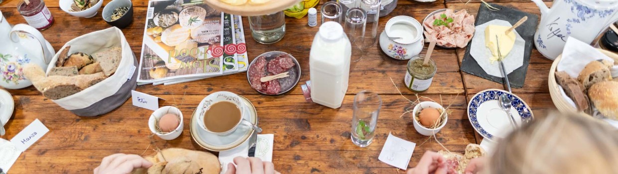 An einem reich gedeckten Tisch mit verschiedenen Frühstücksprodukten genießen Besuchende der HAUS-GARTEN-FREIZEIT gemeinsam die angebotenen Speisen.