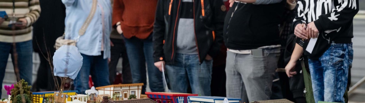 Viele Interessierte betrachten auf der HAUS-GARTEN-FREIZEIT aufmerksam ein detailreiches Miniaturmodell mit unterschiedlichen Häusern und liebevoll gestalteten Gärten.