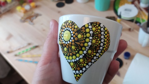 Eine Person hält eine Tasse mit einem Herz darauf in der Hand. Eine Person hält eine Tasse mit einem Herz darauf in der Hand.