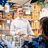 Ein Junger Bäcker verkauft Waren an seinem Stand.