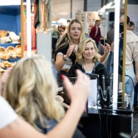 Eine Frau bekommt auf der Messe einen neuen Haarschnitt.