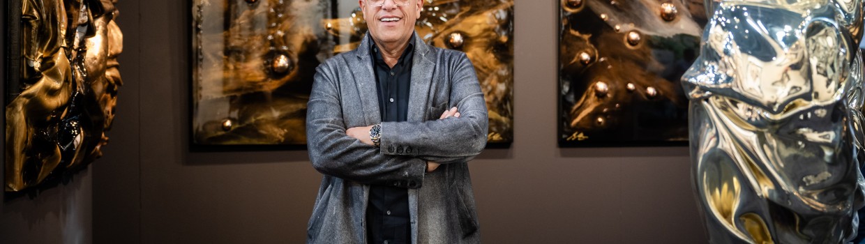 A man stands in the middle of many works of art.