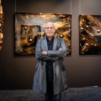 Ein Mann steht in der Mitte von vielen Kunstwerken.