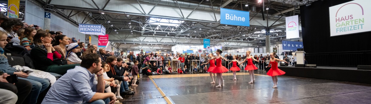 Besucher schauen sich einen Tanz auf einer Bühne an.