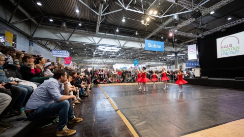 Besucher schauen sich einen Tanz auf einer Bühne an.