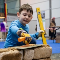 Ein Kind mörtelt eine Mauer.
