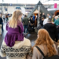 Eine Familie von hinten fotografiert. Sie laufen durch eine Halle der Leipziger Messe.