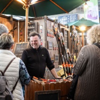 4 Personen unterhalten sich mit einem Mann an einem Verkaufsstand