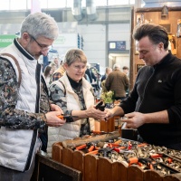 A man and a woman are informed about garden shears at a booth A man and a woman are informed about garden shears at a booth
