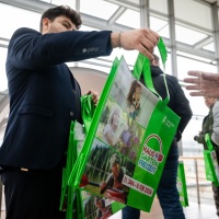 Ein Mitarbeiter der Leipziger Messe verteilt Taschen an Besucher.