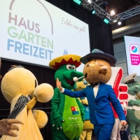 Das Leipziger Messemnännchen ist auf einer Bühne mit vielen anderen Maskotchen.