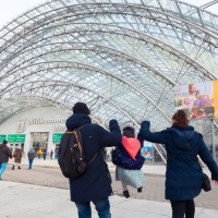 Eine Familie läuft auf den Eingang der Glashalle zu.
